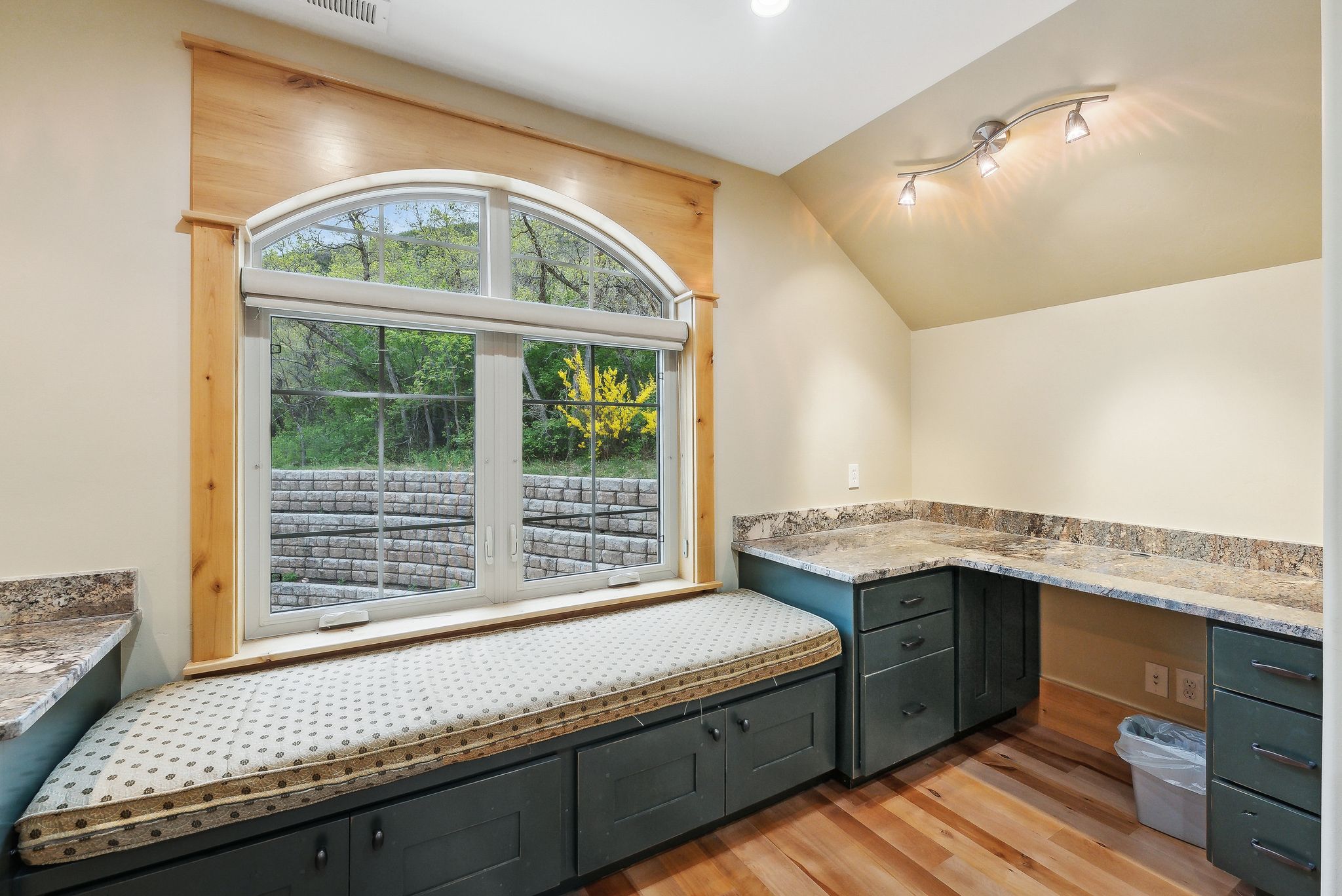 Unfurnished office with light wood finished floors, vaulted ceiling, and built in desk