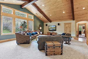 Living area featuring beam ceiling, arched walkways, carpet, recessed lighting, and high vaulted ceiling