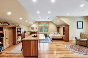 Bedroom with light wood finished floors, vaulted ceiling, and recessed lighting