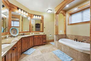 Full bathroom with a bath, double vanity, baseboards, and tile patterned flooring