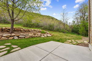 View of grassy yard featuring a patio area and a mountain view
