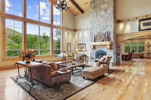 Living area featuring high vaulted ceiling, beamed ceiling, hardwood / wood-style flooring, a stone fireplace, and wooden ceiling
