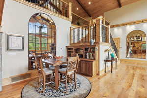Dining area with high vaulted ceiling, wood ceiling, hardwood / wood-style flooring, beam ceiling, and stairway