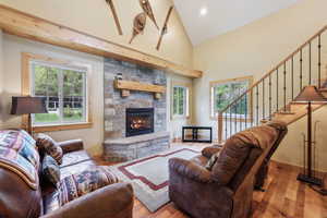 Living room with hardwood / wood-style flooring, healthy amount of natural light, a fireplace, high vaulted ceiling, and stairs