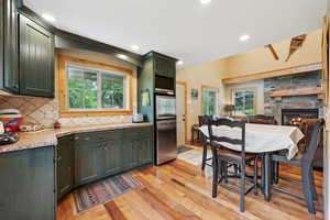 Kitchen featuring appliances with stainless steel finishes, green cabinets, decorative backsplash, light wood-type flooring, and plenty of natural light
