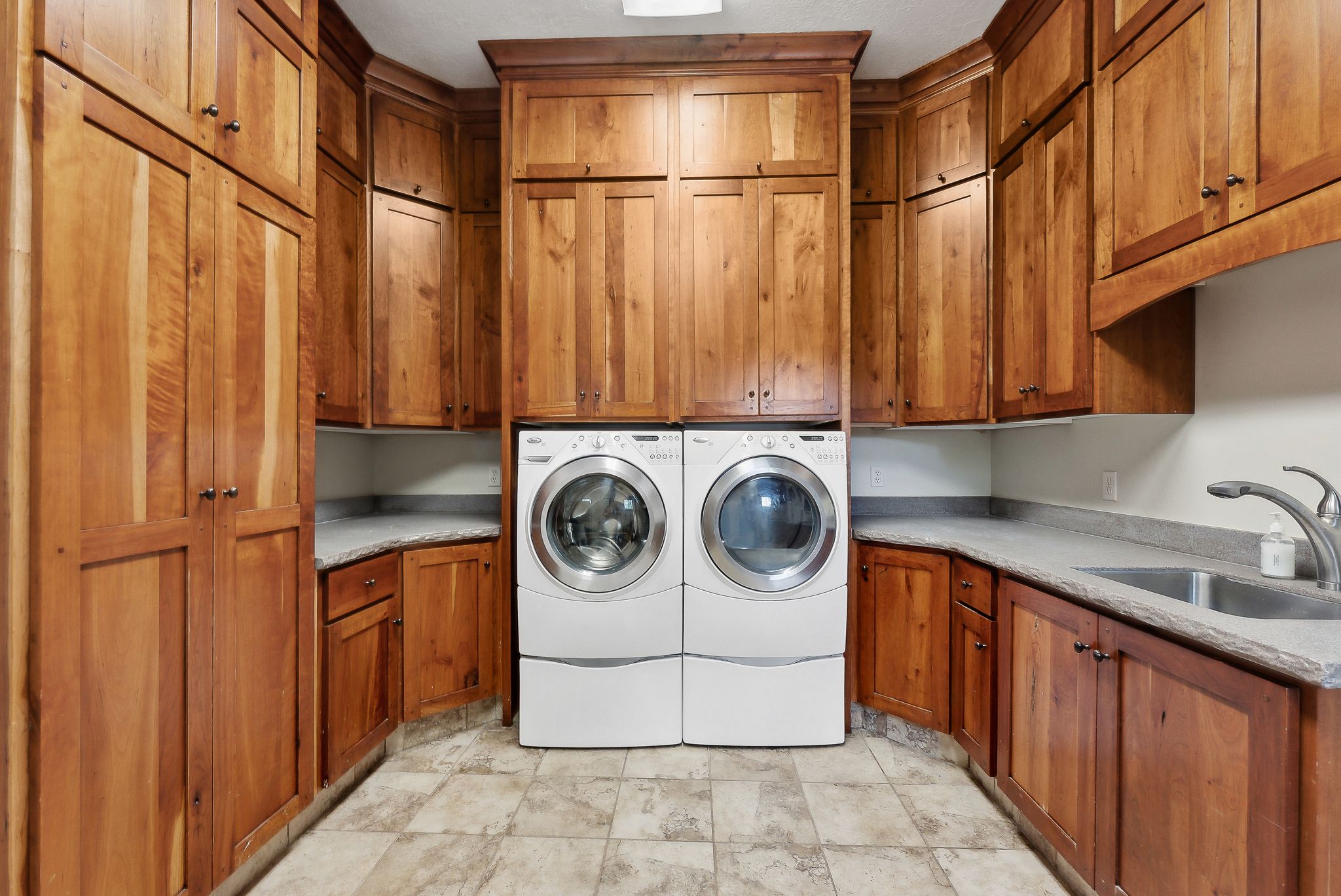 Washroom with cabinet space, separate washer and dryer, and light stone finish flooring