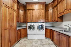 Washroom with cabinet space, separate washer and dryer, and light stone finish flooring