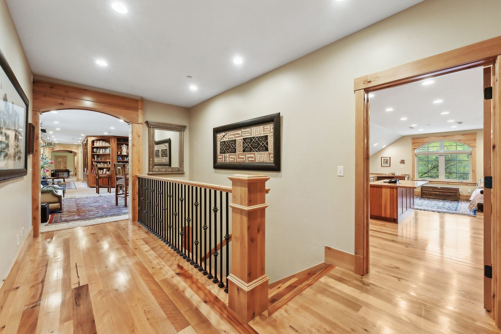 Hallway featuring arched walkways, hardwood / wood-style floors, recessed lighting, an upstairs landing, and baseboards