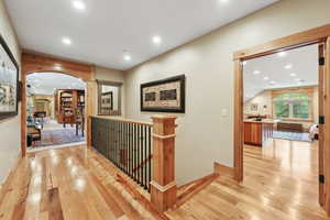 Hallway featuring arched walkways, hardwood / wood-style floors, recessed lighting, an upstairs landing, and baseboards