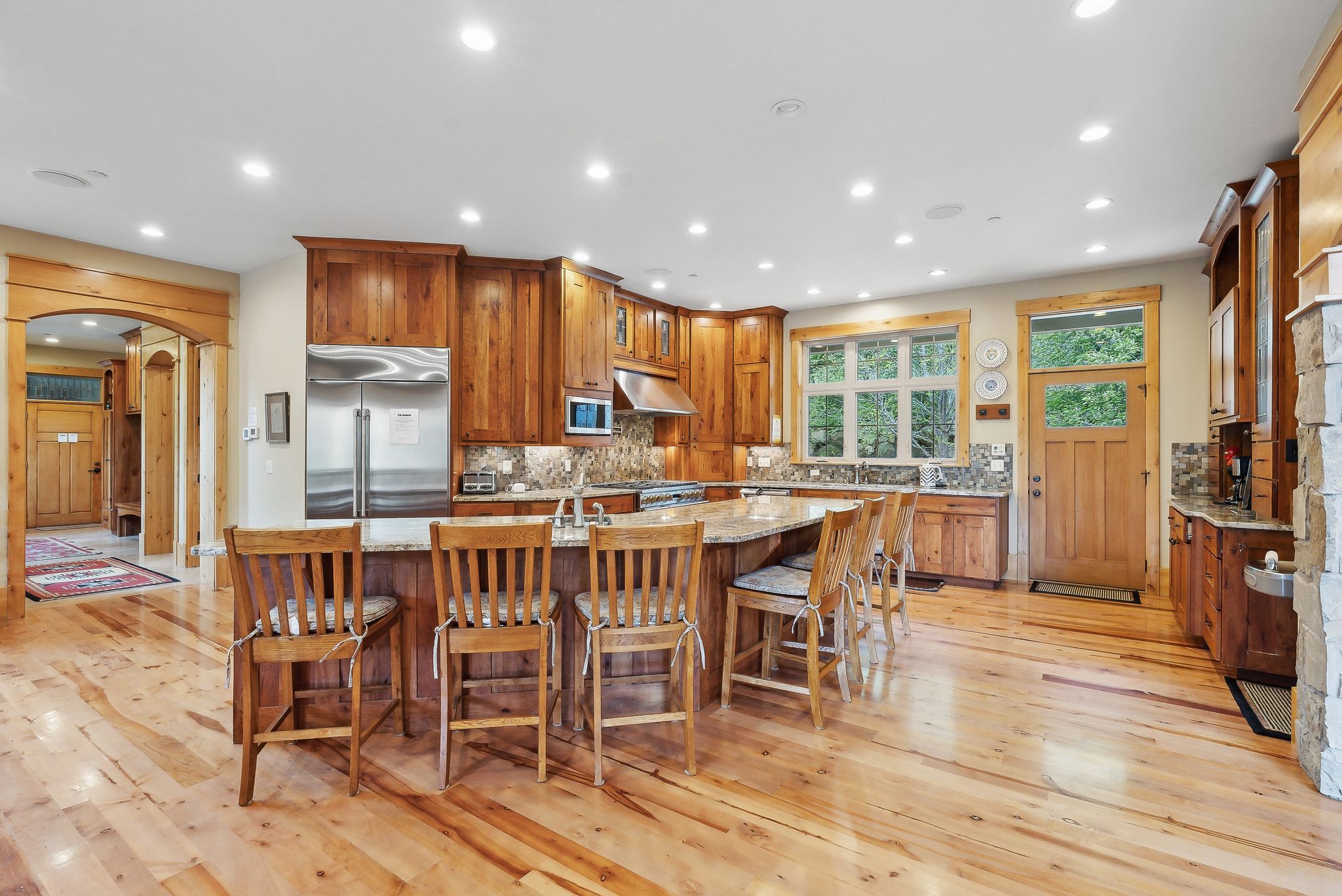 Kitchen with built in appliances, under cabinet range hood, arched walkways, light wood-style flooring, and recessed lighting