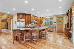 Kitchen with built in appliances, under cabinet range hood, arched walkways, light wood-style flooring, and recessed lighting