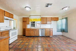 Kitchen featuring white range with electric cooktop, under cabinet range hood, stainless steel dishwasher, brown cabinetry, and a textured ceiling