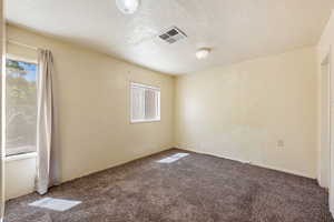 Unfurnished room featuring carpet, a textured ceiling, and a textured wall