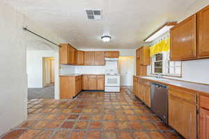 Kitchen with electric range, stainless steel dishwasher, a sink, under cabinet range hood, and a textured ceiling