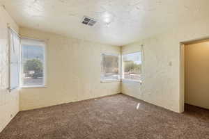 Carpeted empty room featuring a textured wall