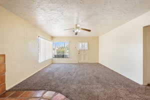 Carpeted empty room featuring a ceiling fan, baseboards, and a textured ceiling