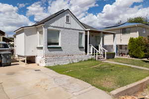 View of front facade with brick siding, a front yard, and board and batten siding