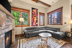 Living area with stone tile floors, beam ceiling, a fireplace, and plenty of natural light