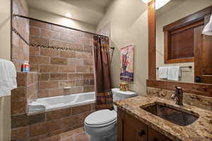 Bathroom featuring tiled shower / bath, vanity, and stone tile flooring