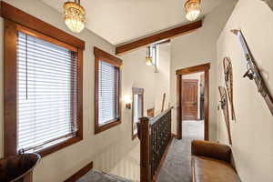Hallway with an upstairs landing, carpet, and beamed ceiling
