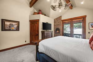 Carpeted bedroom featuring access to outside, beam ceiling, recessed lighting, high vaulted ceiling, and a stone fireplace