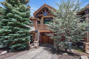 View of front of property featuring driveway, a garage, french doors, a balcony, and stone siding
