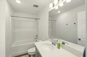 Full bathroom featuring toilet, vanity, shower / bath combination, wood finished floors, and recessed lighting