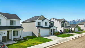 View of front facade featuring an attached garage, driveway, a mountain view, a residential view, and stone siding