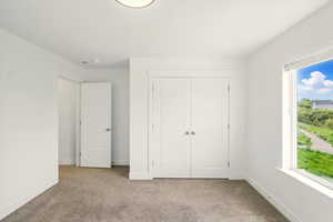 Unfurnished bedroom with carpet floors, multiple windows, and a closet