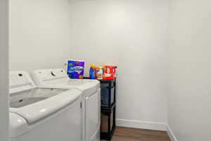 Laundry room with washer and clothes dryer, baseboards, and wood finished floors