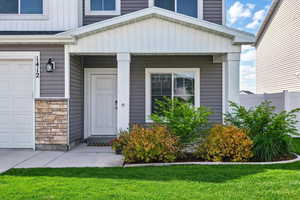 View of exterior entry featuring a garage and stone siding