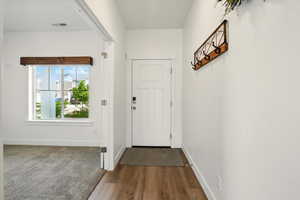 Doorway featuring dark wood-style floors and baseboards