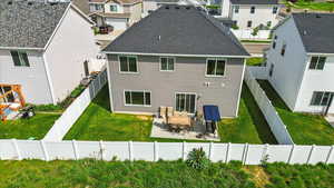 Rear view of house featuring a residential view, a patio area, a lawn, and roof with shingles