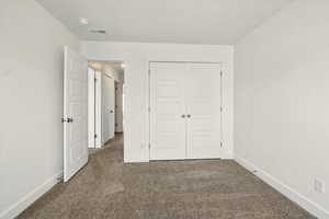 Unfurnished bedroom with carpet, baseboards, and a closet