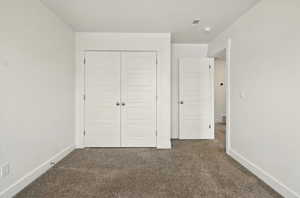 Unfurnished bedroom featuring carpet flooring, a closet, and baseboards