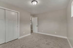 Unfurnished bedroom with baseboards, carpet flooring, and a closet