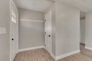 Corridor with light wood-style flooring and baseboards