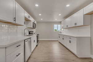 Kitchen featuring stainless steel appliances, a sink, baseboards, recessed lighting, and light countertops