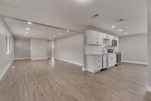 Kitchen featuring stainless steel appliances, baseboards, light countertops, light wood-style flooring, and recessed lighting