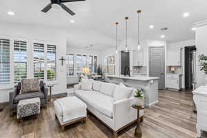 Living area with light wood-type flooring, vaulted ceiling, a ceiling fan, recessed lighting, and baseboards