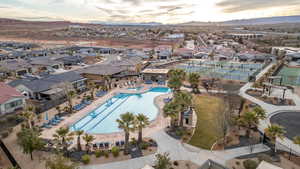 Aerial view of property and surrounding area with a pool, a mountainous background, and nearby suburban area