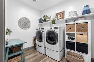 Washroom with wood finished floors, washing machine and dryer, and baseboards