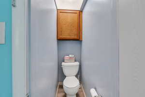 Bathroom featuring wood finished floors, toilet, and baseboards