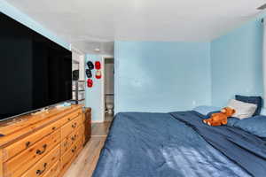 Bedroom featuring light wood-type flooring, ensuite bathroom, and baseboards