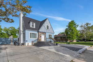 English style home with board and batten siding, a chimney, stone siding, and a shingled roof