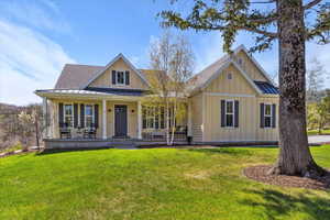 View of front facade featuring a standing seam roof, board and batten siding, a front lawn, and metal roof
