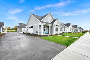 View of front and side of house with board and batten siding, a residential view, a front lawn, a porch, and a shingled roof