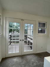 Doorway featuring healthy amount of natural light, french doors, and dark colored carpet