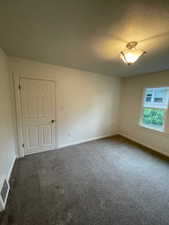 Empty room featuring dark colored carpet and baseboards