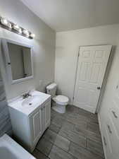 Bathroom with vanity, toilet, and a tub to relax in